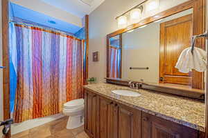 Bathroom featuring a shower with shower curtain, vanity, and toilet