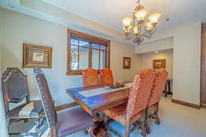 Dining room with carpet floors, a tray ceiling, and an inviting chandelier