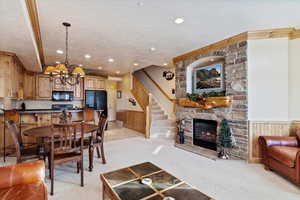 Living room with light carpet, a textured ceiling, an inviting chandelier, a stone fireplace, and wood walls