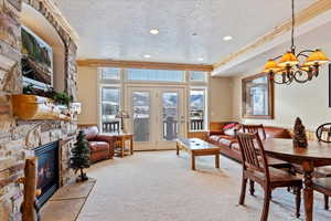 Dining area featuring carpet flooring, ornamental molding, a textured ceiling, a chandelier, and a stone gas  fireplace