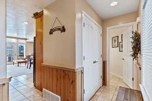 Corridor featuring a textured ceiling, light colored carpet, and wood walls