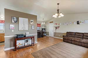 Living room with a chandelier, light hardwood / wood-style flooring, lofted ceiling, and sink