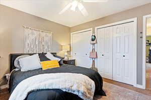 Carpeted bedroom with two closets and ceiling fan