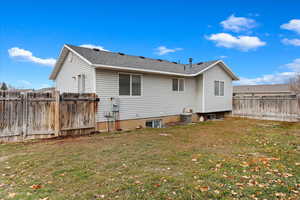 Back of house with a yard and central AC unit