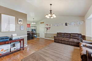 Living room featuring hardwood / wood-style floors, lofted ceiling, and an inviting chandelier