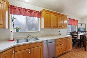 Kitchen with light hardwood / wood-style flooring, stainless steel dishwasher, and sink