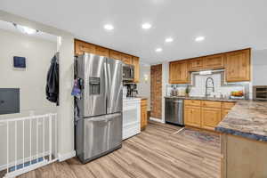 Kitchen featuring electric panel, sink, decorative backsplash, light hardwood / wood-style floors, and stainless steel appliances