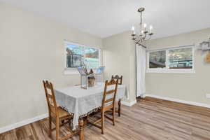 Dining space with light hardwood / wood-style floors and an inviting chandelier