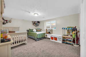 Bedroom featuring a textured ceiling and light colored carpet