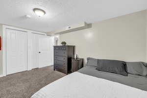 Bedroom with carpet, a textured ceiling, and two closets