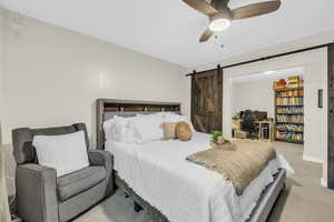 Carpeted bedroom with ceiling fan and a barn door