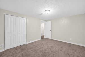 Unfurnished bedroom with carpet, a textured ceiling, and a closet