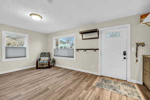 Entrance foyer with light hardwood / wood-style floors and a textured ceiling