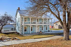 View of front of home with a balcony, a porch, and a storage unit