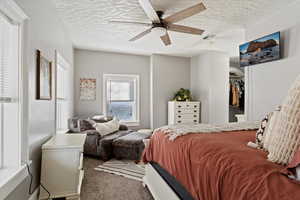 Bedroom featuring a walk in closet, a textured ceiling, ceiling fan, carpet floors, and a closet