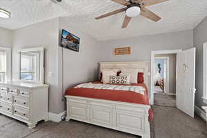 Bedroom featuring light carpet, a textured ceiling, and ceiling fan