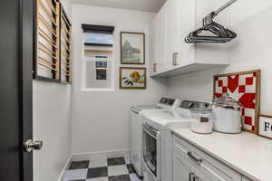 Clothes washing area featuring cabinets, built in drying rack and independent washer and dryer