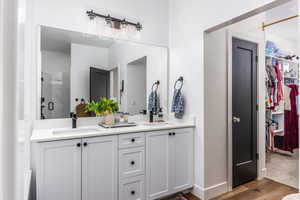 Master Bathroom with walk-in closet, hardwood / wood-style floors, vanity, and a shower with door