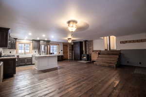 Kitchen featuring dark brown cabinetry, a kitchen island, sink, stainless steel fridge with ice dispenser, and a wood stove