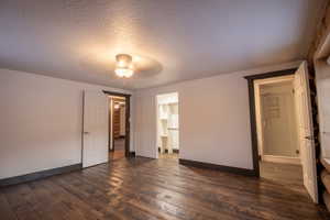 Unfurnished bedroom with ceiling fan, dark hardwood / wood-style floors, and a textured ceiling