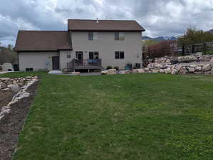Back of property featuring a lawn, a wooden deck, and fence