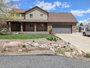 Traditional home with roof with shingles, a front lawn, brick siding, a garage, and driveway