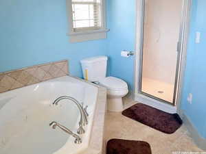 Bathroom with tile patterned flooring, shower with separate bathtub, and toilet