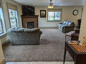 Living room with carpet, ceiling fan, and a fireplace