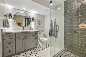 Bathroom with tiled shower, vanity, tile patterned floors, and toilet