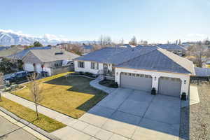 Single story home with a mountain view, a front lawn, and a garage