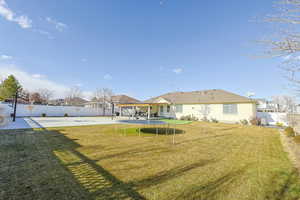 Rear view of property with a lawn, a patio, and a trampoline