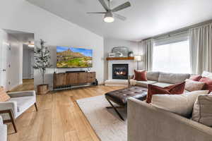 Living room with ceiling fan, light hardwood / wood-style floors, and lofted ceiling