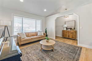 Living room with lofted ceiling, light wood-type flooring, and a healthy amount of sunlight