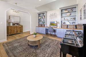 Office space featuring an inviting chandelier, vaulted ceiling, and light wood-type flooring