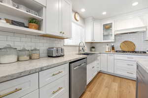 Kitchen with white cabinets, light stone countertops, stainless steel appliances, and tasteful backsplash