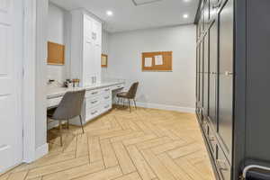 Office space featuring light parquet flooring and built in desk