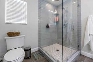 Bathroom featuring toilet and a shower with shower door