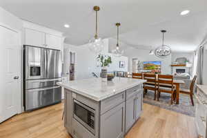 Kitchen featuring ceiling fan, white cabinets, stainless steel appliances, and decorative light fixtures