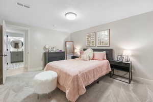 Carpeted bedroom featuring connected bathroom and a textured ceiling