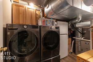 Washroom with hardwood / wood-style floors, separate washer and dryer, and heating unit