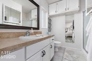 Bathroom featuring toilet, vanity, tile patterned floors, and an enclosed shower