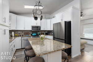 Kitchen featuring a kitchen breakfast bar, backsplash, stainless steel appliances, and a kitchen island