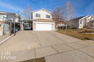 View of front of home featuring a carport, a front yard, and a garage