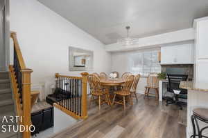 Dining area featuring dark hardwood / wood-style floors, a chandelier, and vaulted ceiling