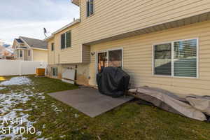 Snow covered rear of property with a patio and a lawn