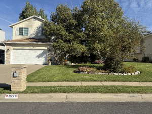 Obstructed view of property featuring a front lawn and a garage