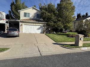 View of front of house with a carport, a garage, and a front lawn