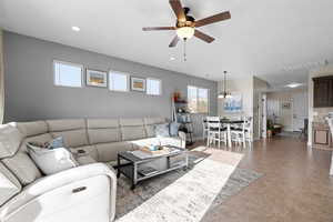 Tiled living room featuring ceiling fan with notable chandelier