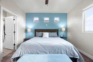 Carpeted bedroom featuring ceiling fan and multiple windows