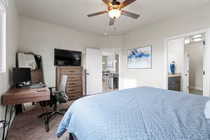 Carpeted bedroom featuring ceiling fan and ensuite bathroom